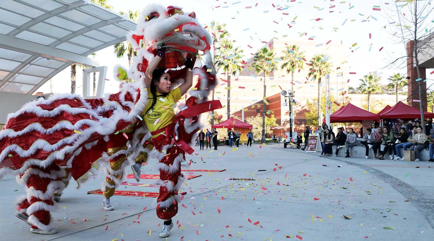 An Asian female student dancing in a lion costume